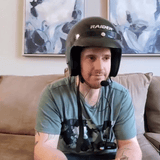 Man testing the Ride Buddy Bluetooth Helmet Headset indoors with a Raider helmet, preparing for hands-free communication and music