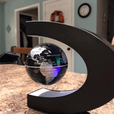 Floating globe light in a C-shaped frame, levitating above a tabletop, illuminated with LED lights displaying continents and countries