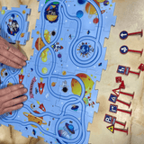 Hands arranging pieces of a space-themed kids puzzle track with miniature road signs, designed to enhance creativity and cognitive skills through imaginative play